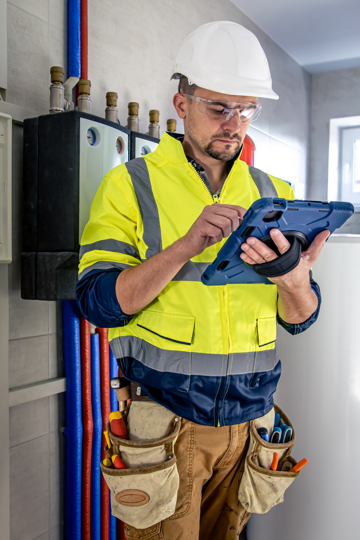 Electricista con uniforme y guantes trabajando en un cuadro eléctrico con interruptores automáticos en carril DIN