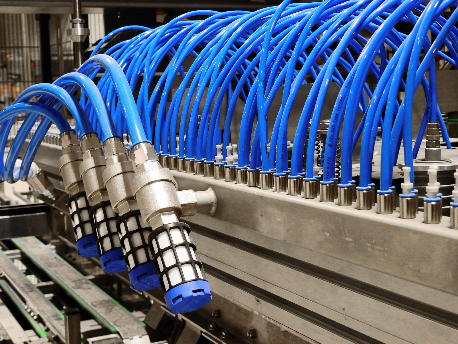Tubos neumáticos azules de aire comprimido conectados a los racores de una máquina industrial