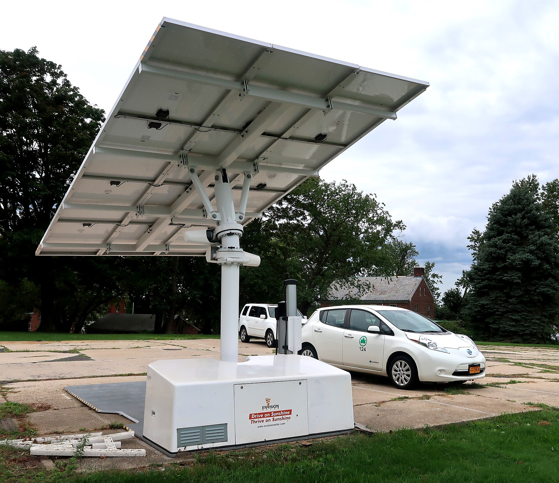 Coche eléctrico cargando en casa junto a una instalación de placas solares fotovoltaicas