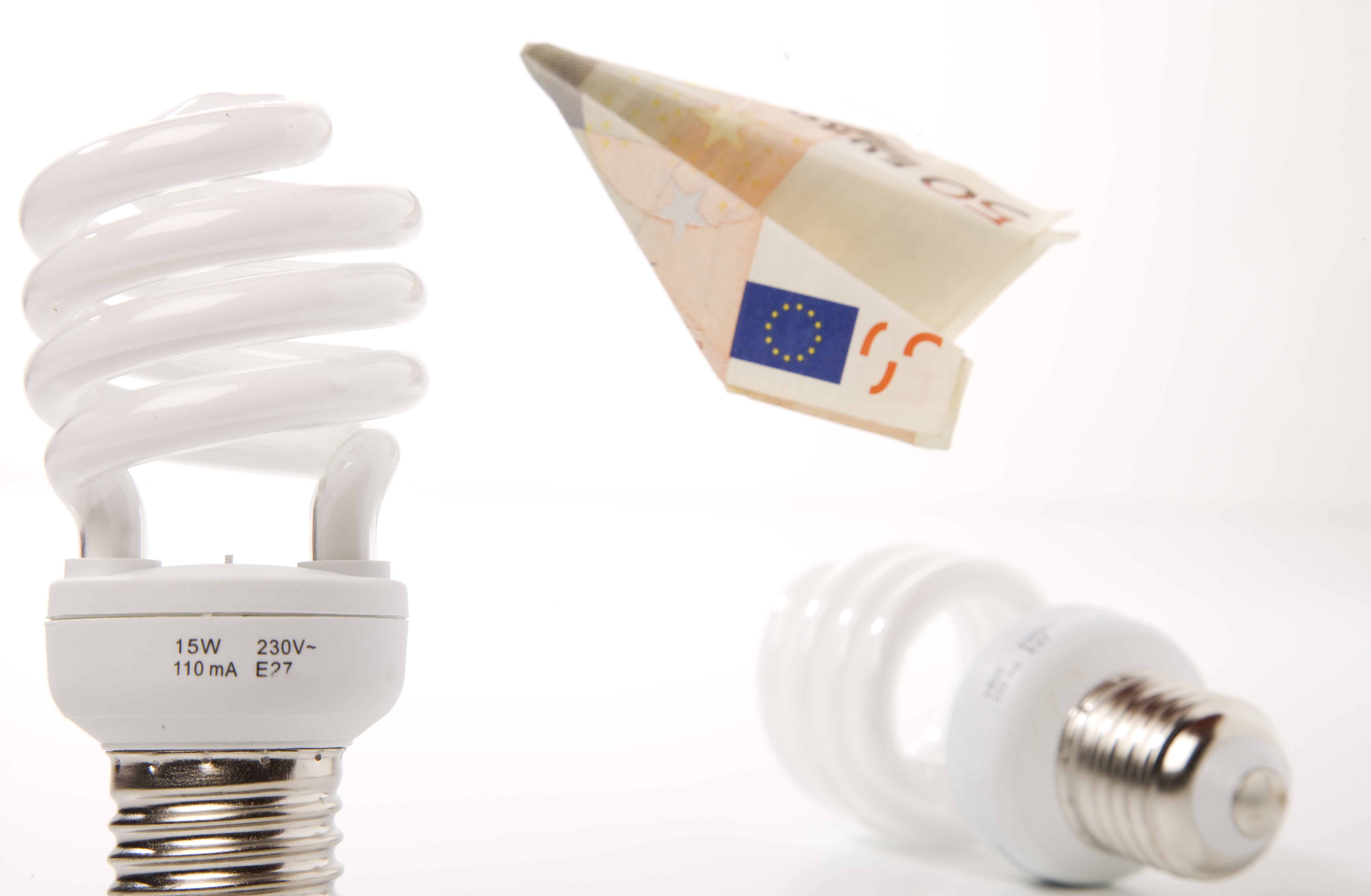 Bombilla de bajo consumo junto a billetes y un contador eléctrico, símbolo de ahorro energético rentable