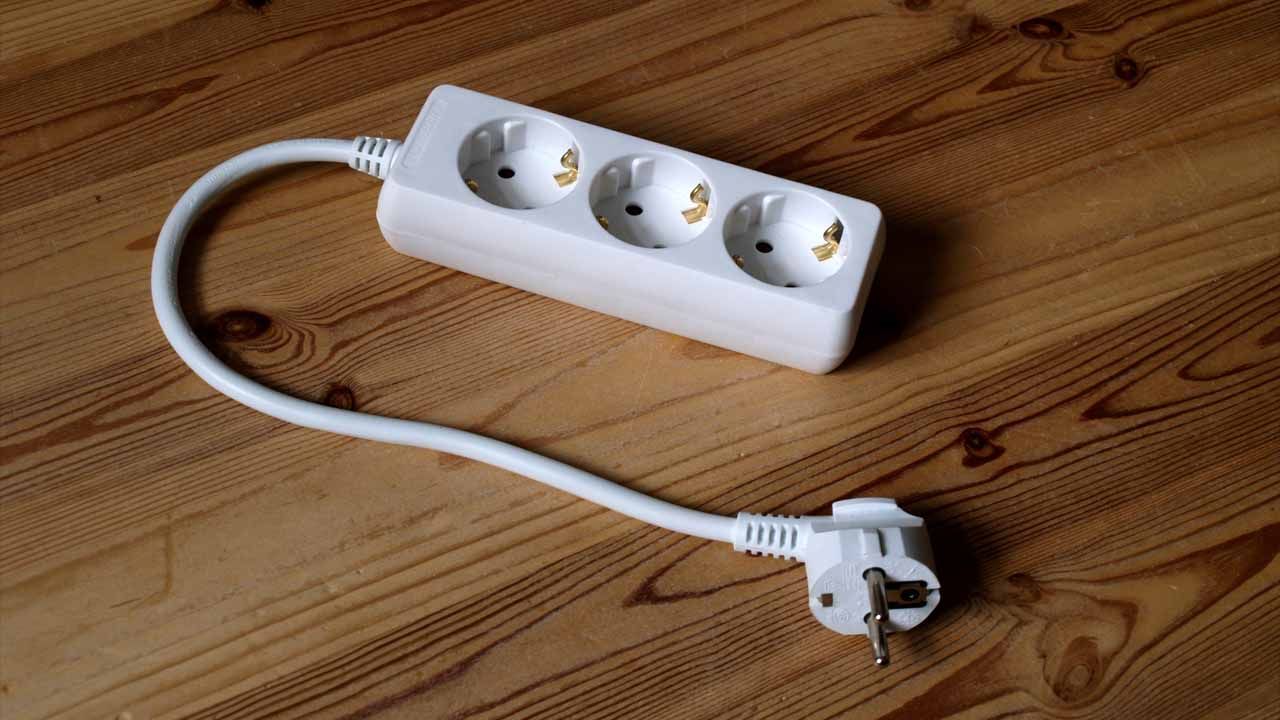 Regleta de enchufes múltiple con cable conectada, lista para agrupar los aparatos de un mueble del salón
