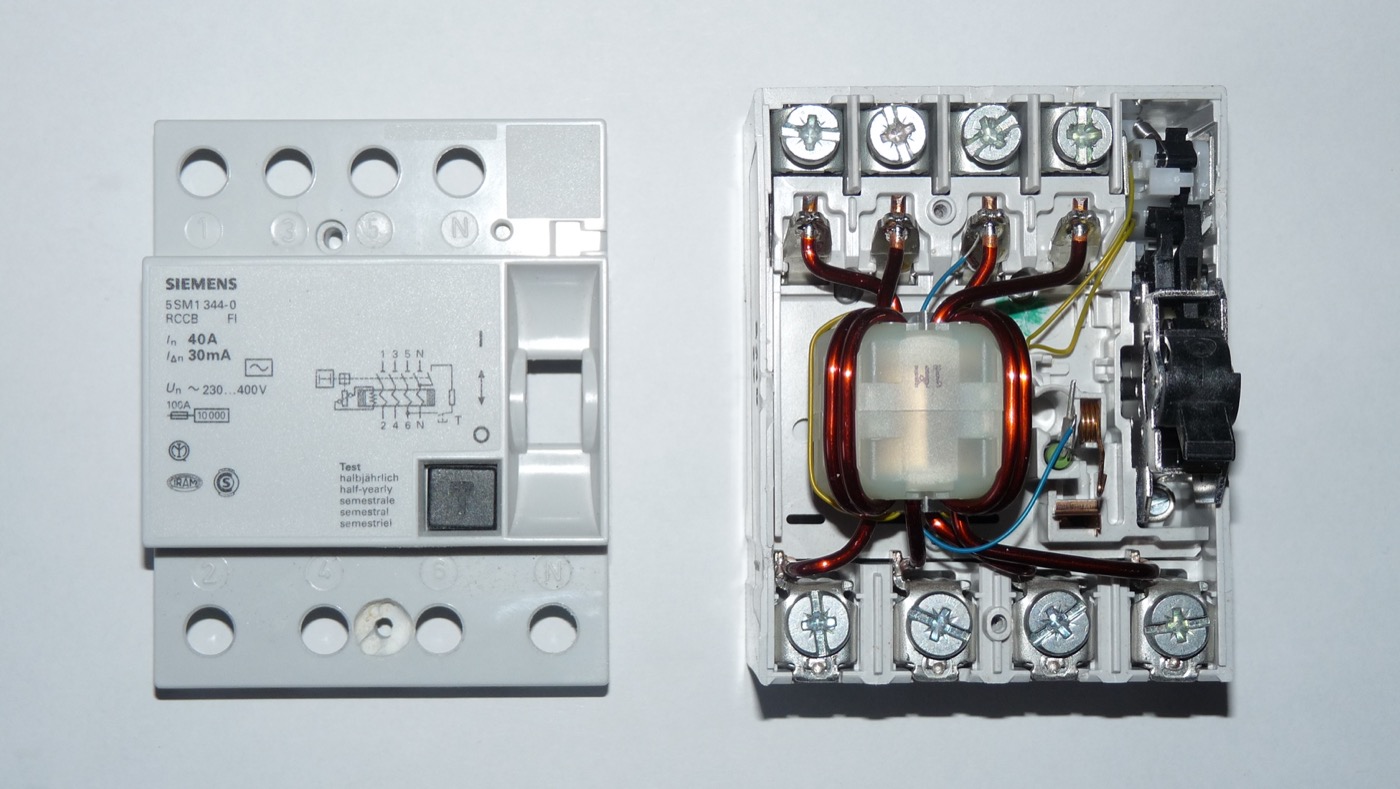 Interruptor diferencial de 40 A y 30 mA, uno cerrado y otro con la carcasa retirada mostrando el toroidal interior