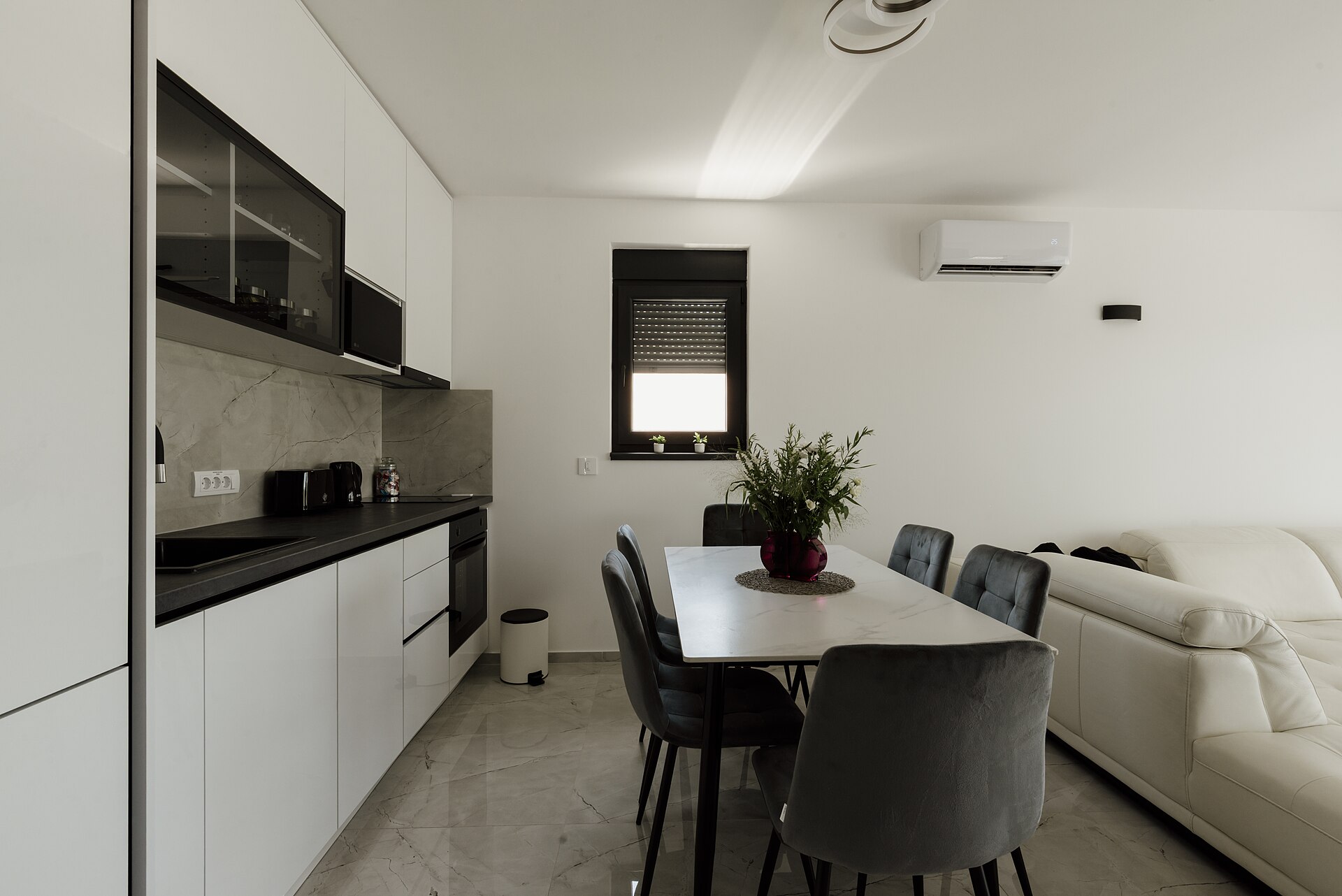 Cocina moderna con horno, placa de inducción y equipo de aire acondicionado en el salón de una vivienda