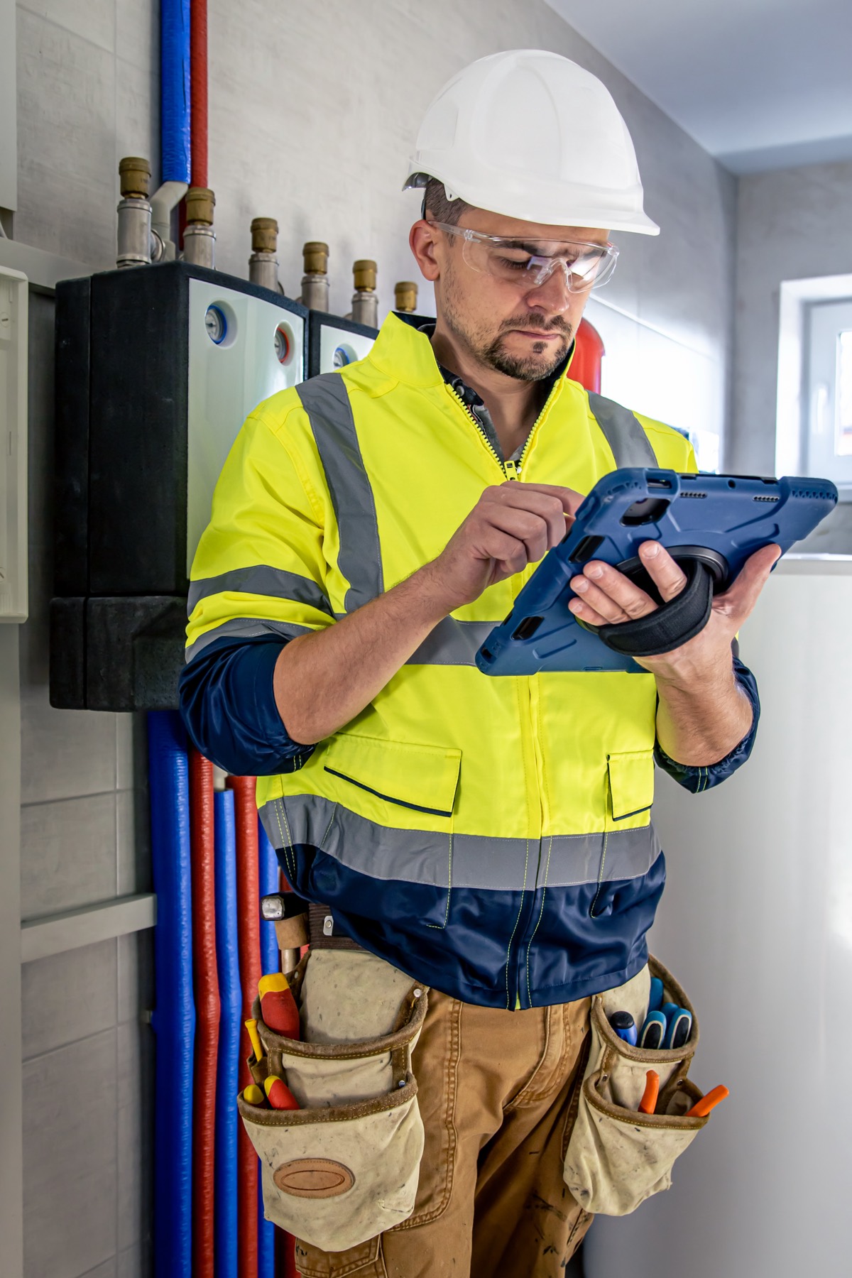 Técnico electricista con casco y guantes revisando los interruptores automáticos de un cuadro eléctrico