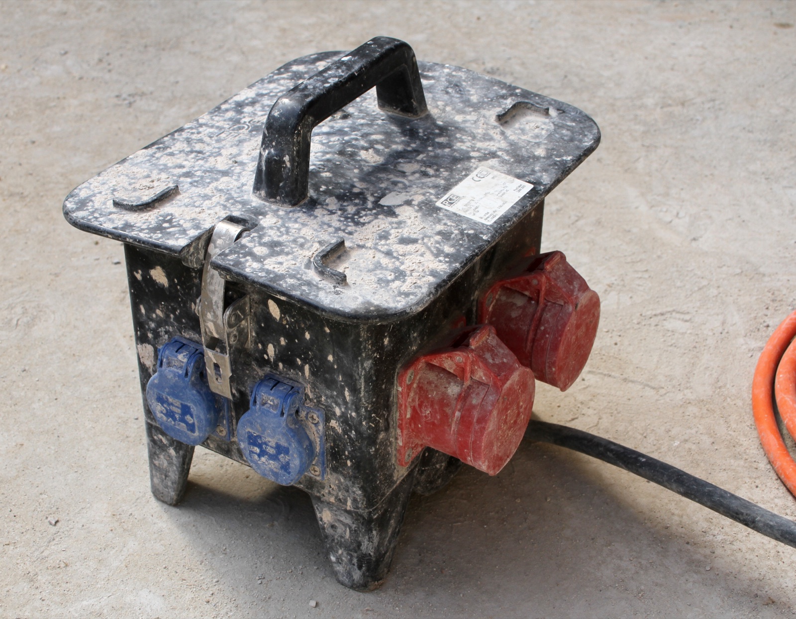 Cuadro eléctrico portátil de obra con bases de toma de corriente azules y rojas y manguera de goma