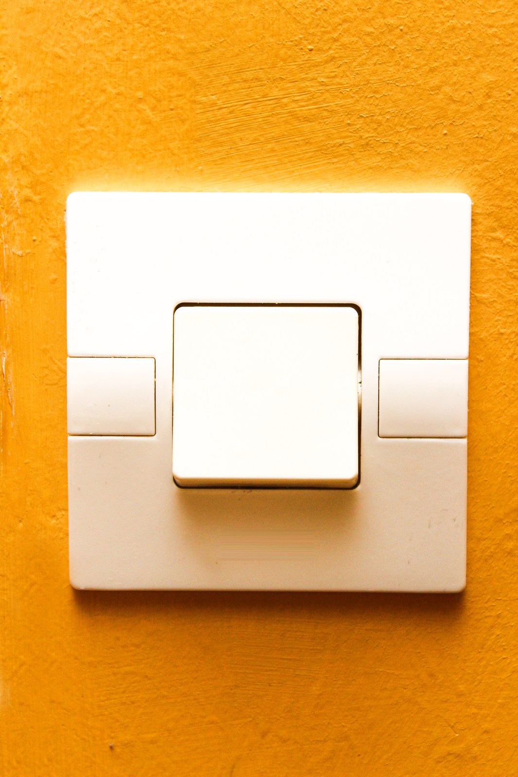 Interruptor de luz blanco de pared sobre una pared naranja, listo para sustituirse por un interruptor inteligente
