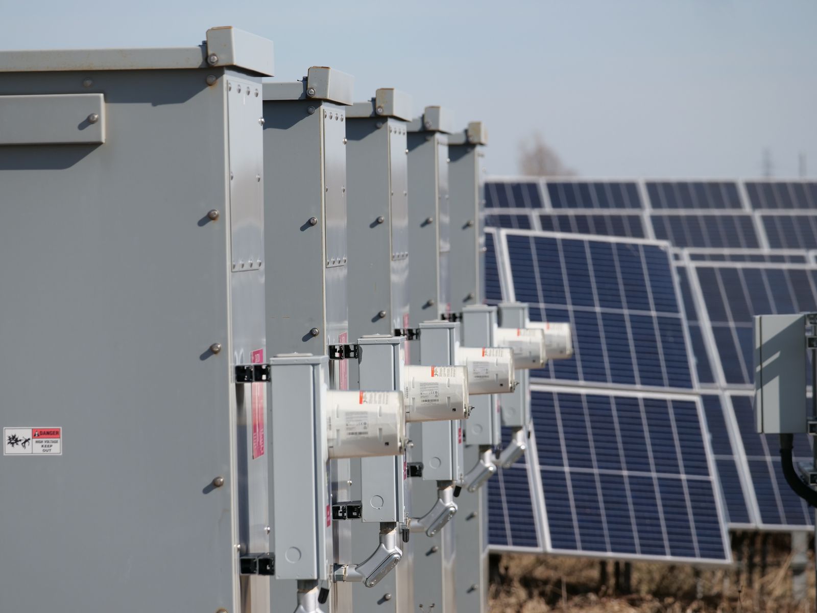 Fila de inversores y armarios eléctricos de una instalación fotovoltaica junto a los paneles solares