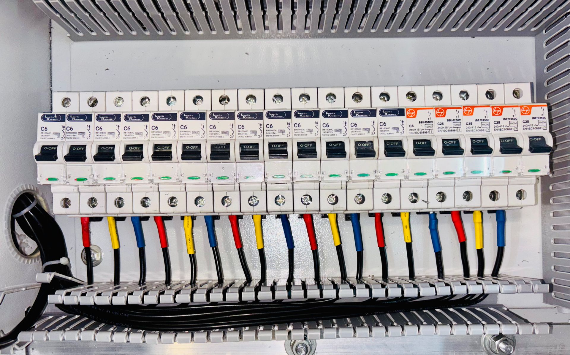 Fila de interruptores automáticos magnetotérmicos C6 y C25 en un cuadro eléctrico con cableado ordenado por colores