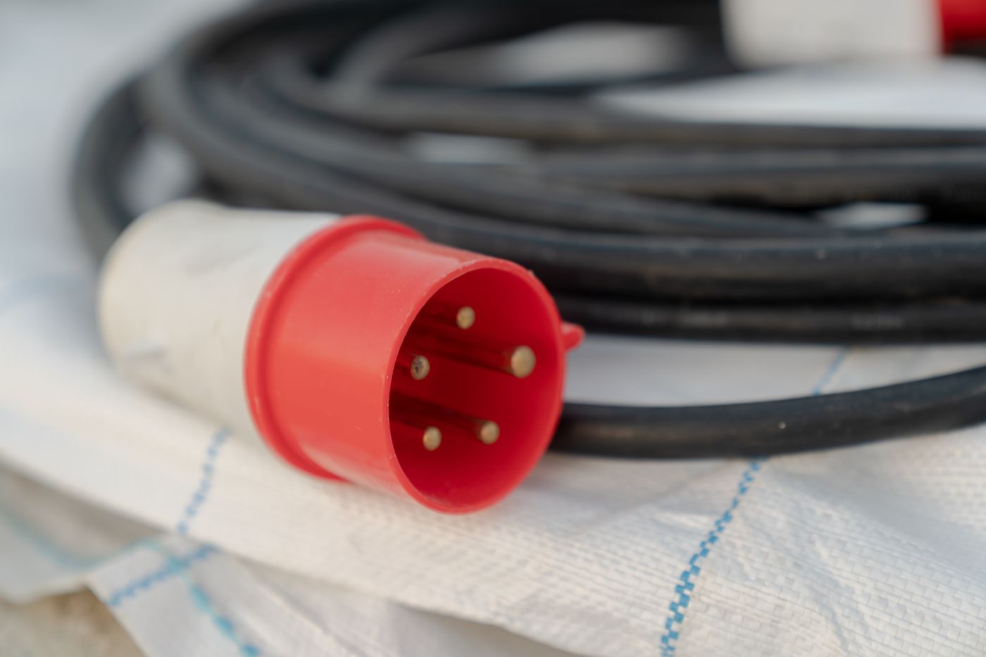 Clavija industrial CETAC roja de cinco polos conectada a una manguera de cable negra